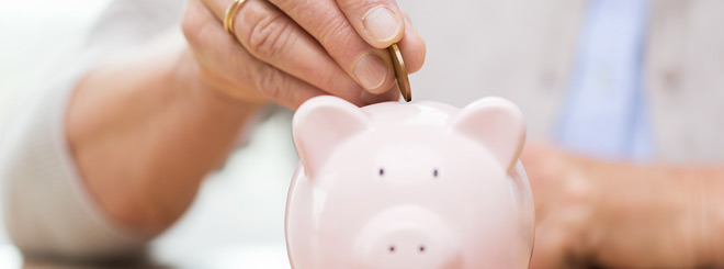 Close up of woman dropping a coin into a piggy bank